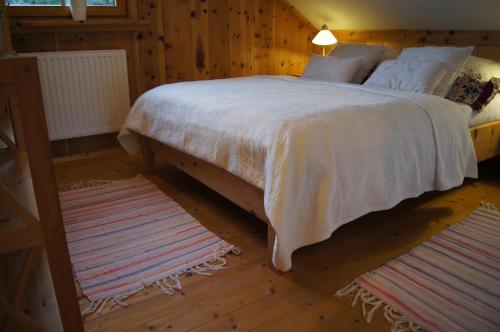 a bedroom with a large white bed with wooden floors at Chalet Steiermark in Pusterwald