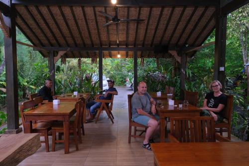 un grupo de personas sentadas en mesas en un restaurante en Java Turtle Lodge Meru Betiri, en Banyuwangi