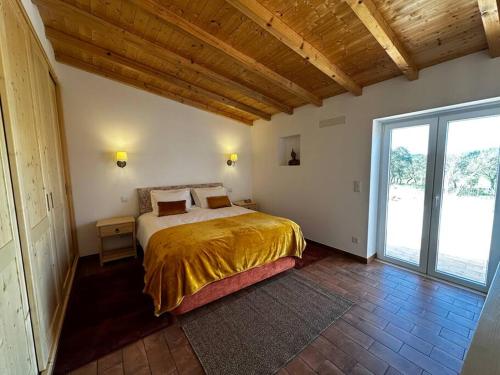 a bedroom with a bed and a large window at Monte da Caniveta - Casa do Avô in São Luis