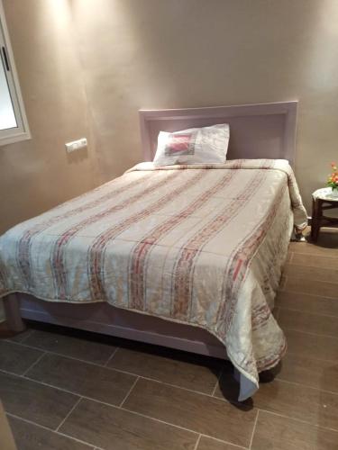 een bed met een deken en een kussen erop bij Villa avec piscine in Plage de Mehdia