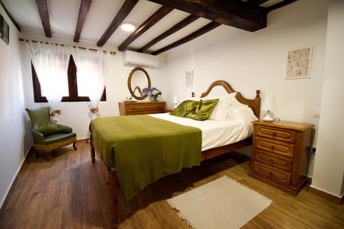 1 dormitorio con 1 cama con manta verde y silla en Casa Rural El Sobraillo, en Villanueva de la Vera