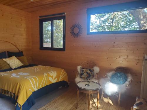 a bedroom with a bed and a table and a window at Tiny chalet dans la campagne lauragaise in Baziège