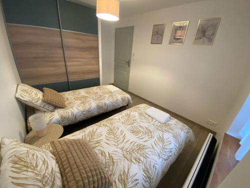 ein kleines Zimmer mit 2 Betten und einem Stuhl in der Unterkunft La Petite Maison du Canal in Digoin