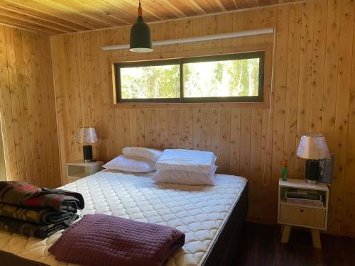 1 dormitorio con 1 cama con sábanas blancas y ventana en Cabaña rio trancura, en Pucón