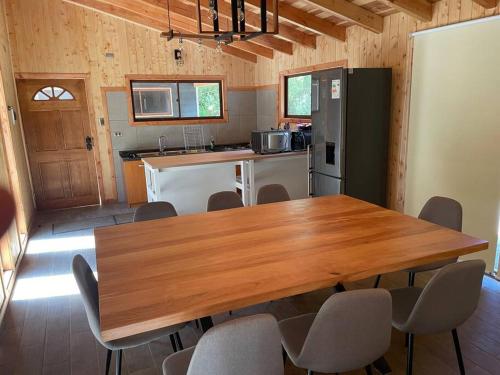 una cocina con una gran mesa de madera y sillas en Cabaña rio trancura, en Pucón