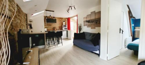 a living room with a blue couch and a kitchen at Appartement de Charme - Centre Ville in Châteaubriant