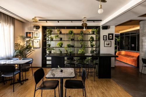 a restaurant with tables and chairs and plants on the wall at The Modernist Athens in Athens