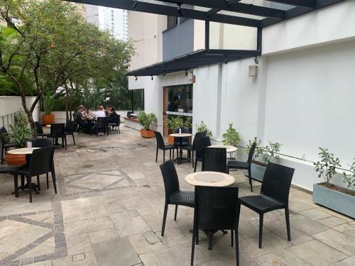 un patio con tavoli, sedie e posti a sedere di Flat Jardim Paulista a San Paolo