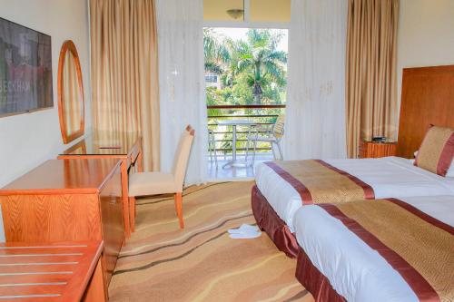 Habitación de hotel con cama, escritorio y balcón. en Mbale Resort Hotel, en Mbale