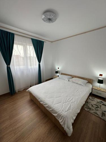 a bedroom with a large white bed with blue curtains at Apartament Pruneanu in Câmpia Turzii