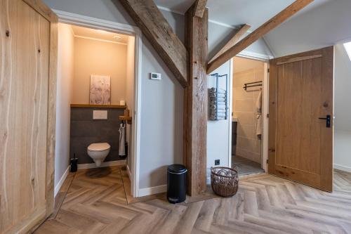 a bathroom with a toilet and wooden walls at Jantje Slot Hoeve in Oosterzee