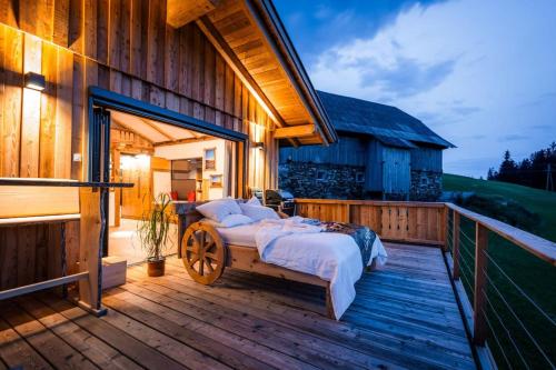 a bed on a wooden deck with a barn at Unterkircher Chalet in Arriach