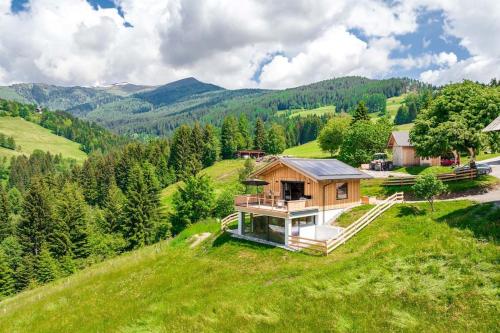 una casa en la cima de una colina con montañas en el fondo en Unterkircher Chalet, en Arriach