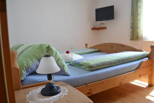 a bed with green pillows and a lamp on a table at Gästehaus Taucher in Bad Blumau