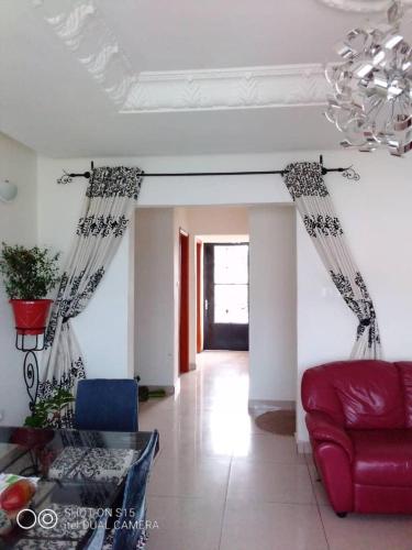 a living room with a red couch and a chandelier at Appartement luxueux de Bonaberi in Douala