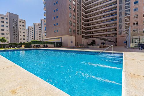 a large blue swimming pool in front of tall buildings at Amazing apartments in the modern Coruña building, near the beach, pool & garage in Villajoyosa