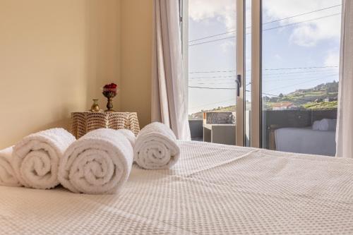 ein Schlafzimmer mit Handtüchern auf einem Bett mit Fenster in der Unterkunft Villa Angela- Madeira Inn Group in Calheta