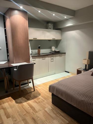 a bedroom with a bed and a desk and a kitchen at Apartament 117 in Krynica Zdrój