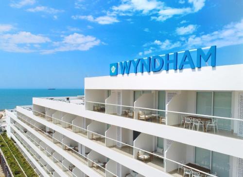 a white building with the ocean in the background at Wyndham Santa Marta Aluna Beach Apartments in Santa Marta
