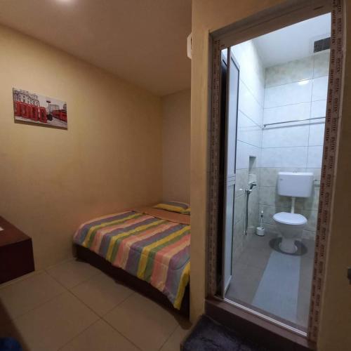 a bedroom with a bed and a shower and a toilet at EASY HOMESTAY LUKUT NS in Port Dickson