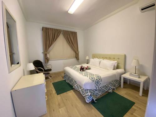 ein Schlafzimmer mit einem Bett, einem Tisch und einem Stuhl in der Unterkunft فاوتشر فان بيتش in Durrat Al-Arus