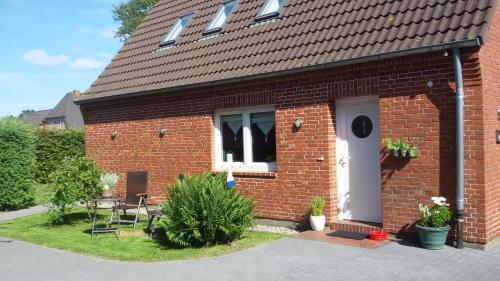 ein rotes Backsteinhaus mit einer weißen Tür und einem Fenster in der Unterkunft Harksen Hüs in Klixbüll