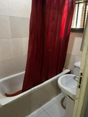 ein Badezimmer mit einem roten Duschvorhang und einem WC in der Unterkunft OD-V!CK'S BUDGET ROOMS, 24HR POWER, SECURITY, DSTV in Abuja