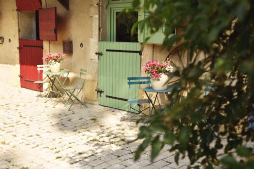 un grupo de sillas y una puerta con flores. en Embarben Maison d'hôtes, en Saint-Chamas