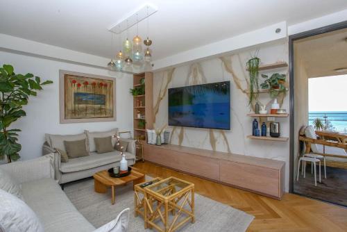 a living room with a couch and a tv at Ultra Luxury 3BR Beach Apartment in Tel Aviv