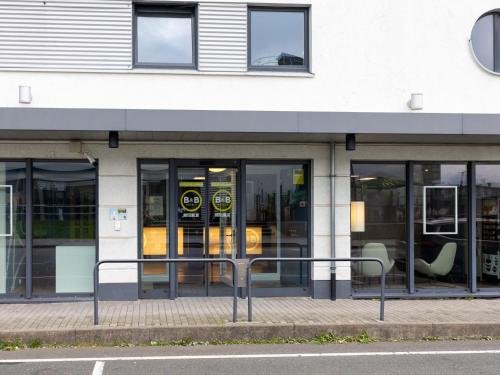 un edificio con puertas de cristal y sillas en B&B HOTEL Frankfurt-Hahn Airport, en Lautzenhausen