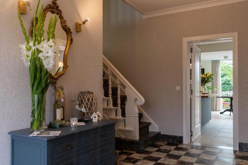 Cette chambre est dotée d'un escalier et d'un vase de fleurs sur une commode. dans l'établissement B&B Gellick, à Lanaken