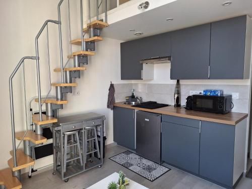 une cuisine avec des armoires bleues et un escalier en colimaçon dans l'établissement Jolie studio Nice Magnan, à Nice