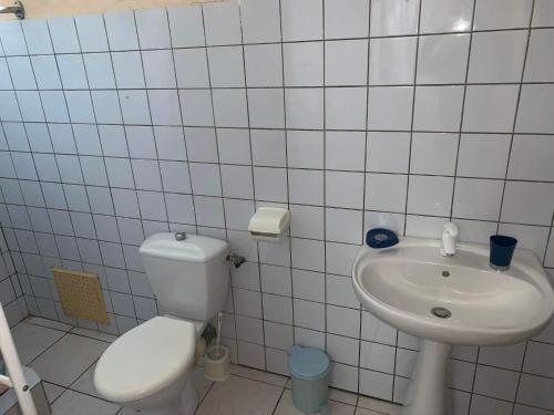 La salle de bains blanche est pourvue de toilettes et d'un lavabo. dans l'établissement Domaine de Kanelle, à Rivière-Pilote