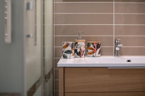 a bathroom sink with two cups on top of it at Chestnut House Appartment in Le Mée-sur-Seine