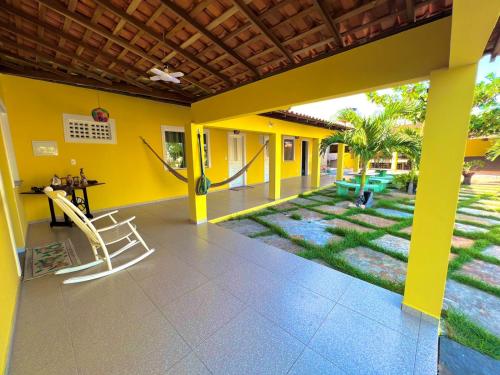 ein gelbes Haus mit einer Veranda mit Schaukel in der Unterkunft Pousada Sitio Sossego dos Lençóis in Barreirinhas