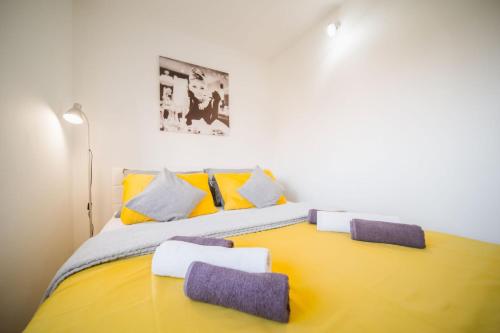 Un dormitorio con una cama amarilla con almohadas moradas y amarillas en Apartment Sacramento centar Varaždin en Varaždin