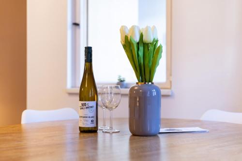a bottle of wine and a vase of flowers on a table at Apartments an der Oper - Innenstadt - Zentral - Küche - Wifi - Powered by Ko-Living in Halle an der Saale