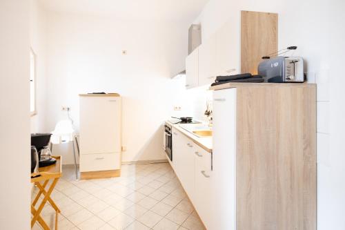 a white kitchen with a sink and a refrigerator at Apartments an der Oper - Innenstadt - Zentral - Küche - Wifi - Powered by Ko-Living in Halle an der Saale