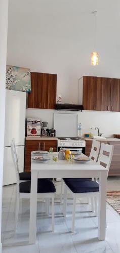 Una cocina blanca con una mesa y sillas blancas. en Ammoudaries appartment, en Lakkíon