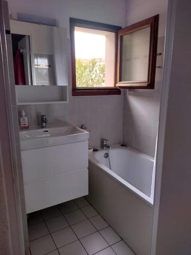 une salle de bain blanche avec une baignoire et un lavabo dans l'établissement Appart - résidence avec piscine St jean de Monts, à Saint-Jean-de-Monts