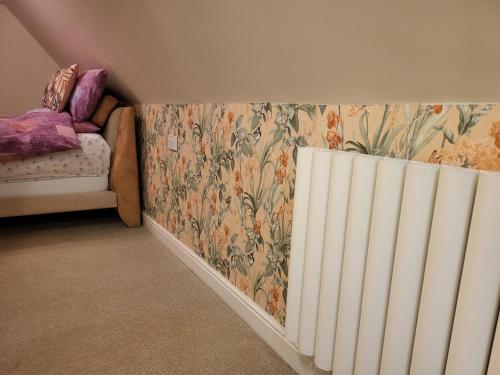 a bedroom with a radiator and floral wallpaper at Tarn Cottage in Skegness