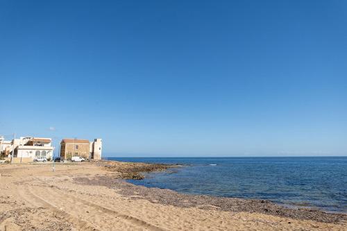 a sandy beach with houses and the ocean at Casa malacala in Calabernardo