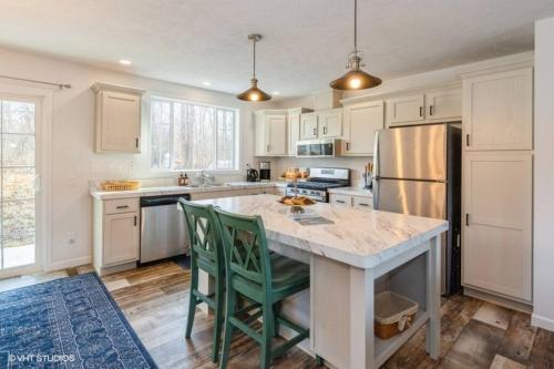 a kitchen with white cabinets and a kitchen island with green chairs at Archer's Retreat Sleeps 10 in Sawyer