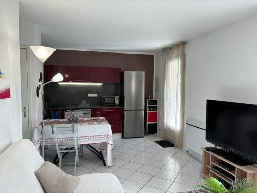 a living room with a table and a kitchen at Les clés de Jonzac-conciergerie Nid de Douceur in Ozillac