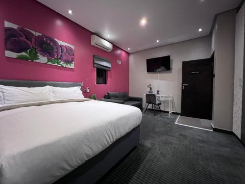a bedroom with a white bed and a pink wall at The Raz in Harrismith