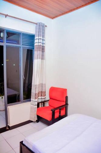 um quarto com uma cadeira vermelha e uma janela em Iwawe by IBC- Room 1 em Kigali