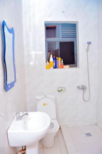 a white bathroom with a toilet and a sink at Iwawe by IBC- Room 1 in Kigali