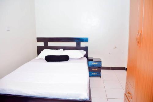 um quarto com uma cama com lençóis brancos e almofadas em Iwawe by IBC- Room 1 em Kigali