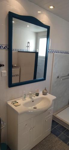 een badkamer met een witte wastafel en een spiegel bij LESSENCIEL in Tournay