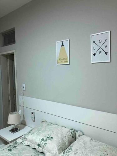 a white bedroom with a bed and a lamp on a table at Apartamento C na vila-alta em Crato in Crato